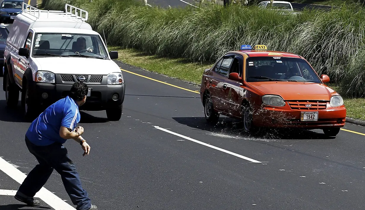 Sebuah taksi dilempar telur oleh rekannya karena menolak ikut unjuk rasa di San Jose, Senin (1/2).  Mereka melakukan protes terhadap taksi Uber yang mulai beroperasi di Kosta Rika. (REUTERS/Juan Carlos Ulate)