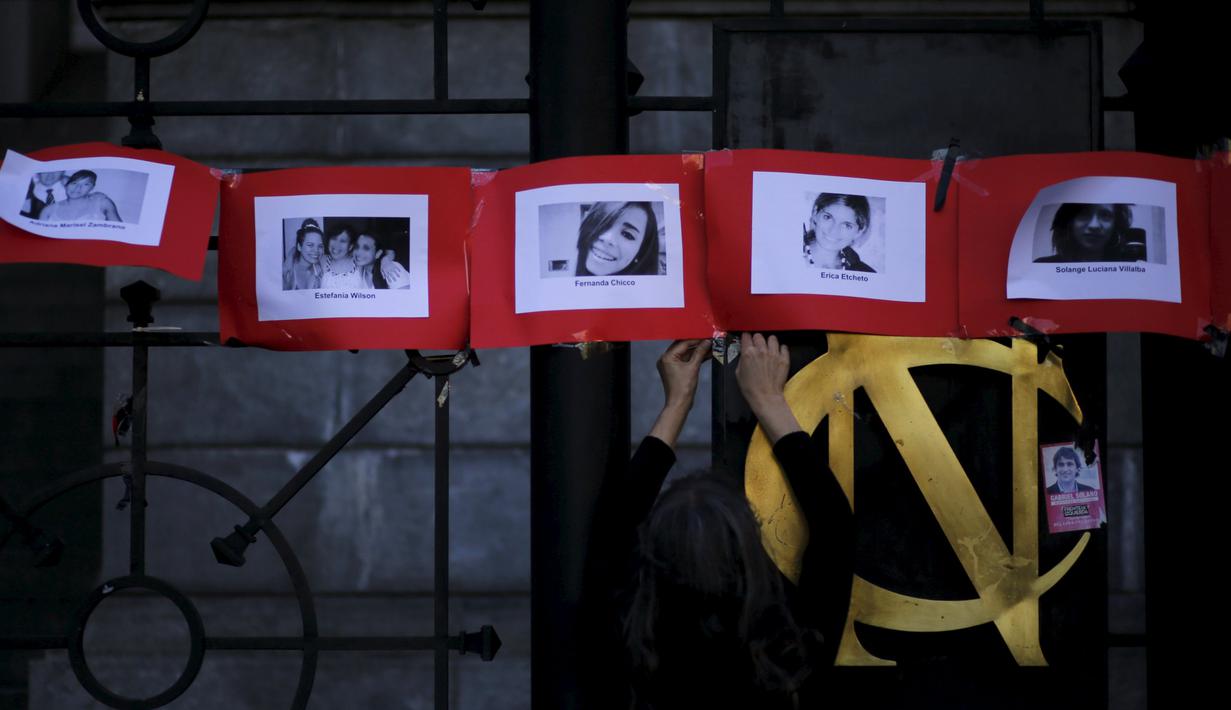 Seorang wanita menggantung foto korban kekerasan dalam rumah tangga saat memperingati Hari Internasional untuk Penghapusan Kekerasan terhadap Perempuan di Buenos Aires, Argentina, Rabu (25/11). (REUTERS/Marcos Brindicci)