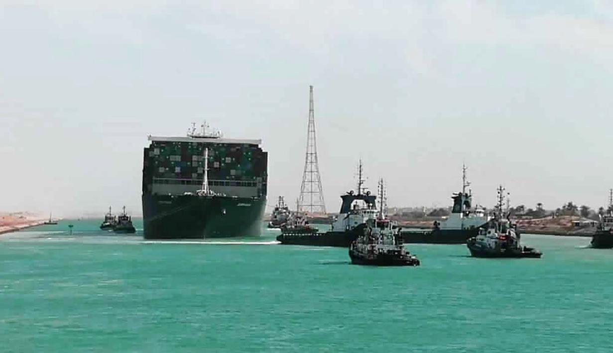 Kapal kargo Ever Given ditemani kapal tunda saat melaju di Terusan Suez, Mesir, Senin (29/3/2021). Ratusan kapal sedang menunggu untuk melewati kanal yang menghubungkan Mediterania ke Laut Merah. (Suez Canal Authority via AP)
