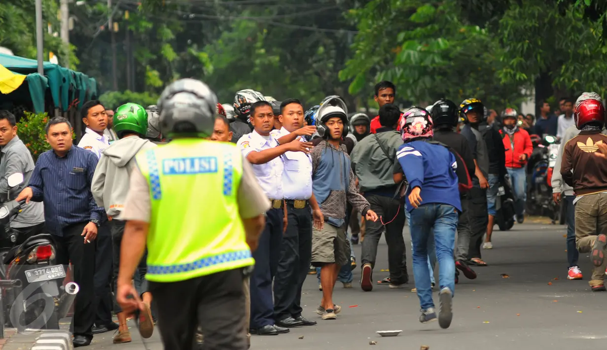Seorang polisi berusaha membubarkan aksi lempar batu antara sopir taksi yang melakukan unjuk rasa dengan pengemudi ojek online, di kawasan Sudirman, Jakarta, Selasa (22/3). (Liputan6.com/Faisal R Syam)