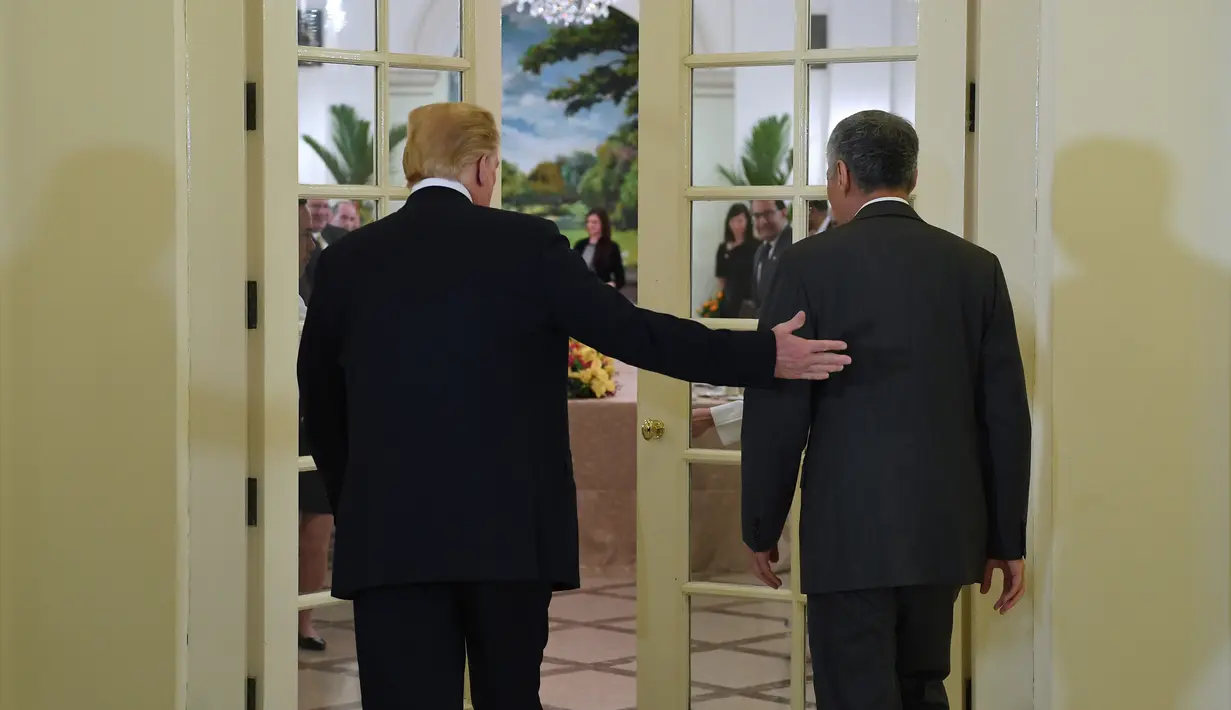 Presiden AS Donald Trump (kiri) bersama PM Singapura Lee Hsien Loong (kanan) memasuki ruangan untuk makan siang bersama di Istana Negara Singapura, Senin (11/6). (SAUL LOEB/AFP)