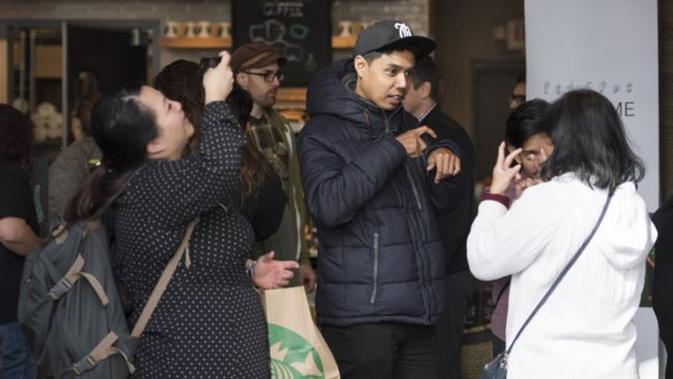 Para pengunjung berbincang menggunakan bahasa isyarat di kafe Starbucks yang pertama mempekerjakan karyawan penyandang tuna rungu atau mengalami kesulitan pendengaran, di Washington DC, 23 Oktober 2018. (AFP via VOA Indonesia)