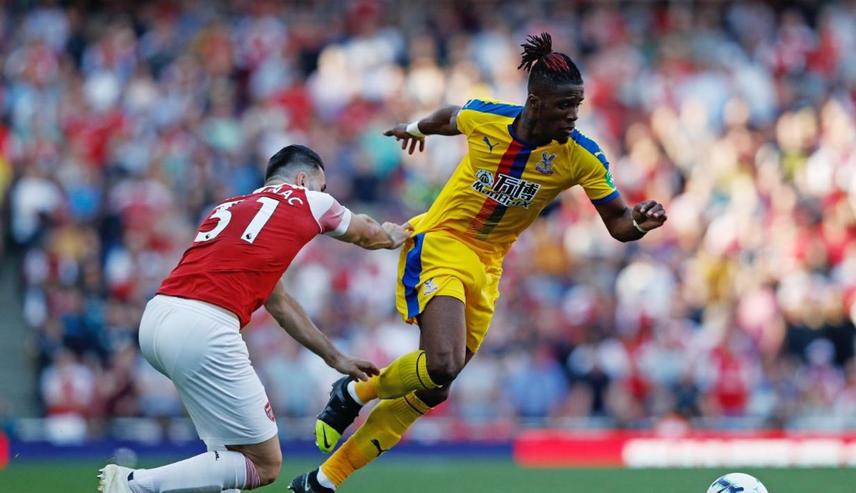 Aksi Wilfried Zaha melewati Sean Kolasinac pada laga lanjutan Premier League yang berlangsung di Stadion Emirates, Minggu (21/4). Arsenal kalah 2-3 kontra Crystal Palace. (AFP/Adrian Dennis)