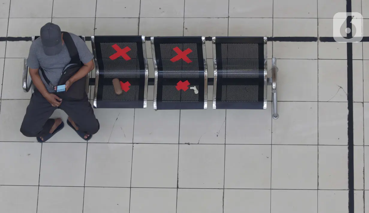 Calon penumpang melihat ponsel sambil menanti waktu keberangkatan bus Antar Kota Antar Provinsi di Terminal Bus Terpadu Pulo Gebang, Jakarta, Kamis (31/12/2020). Memasuki libur pergantian tahun sejumlah calon penumpang terus berdatangan di Terminal Bus Terpadu Pulo Gebang. (Liputan6.com/Helmi Fithri