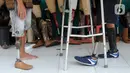 Ronald Regen (33), perajin yang juga penyandang disabilitas membantu pelanggan mencoba kaki palsu di Dusun IV Rawailat, Desa Dayeuh, Cileungsi, Bogor, Jawa Barat, Selasa (29/3/2022). UMKM kaki palsu yang sempat bangkrut akibat pandemi COVID-19 mulai bangkit sejak awal tahun.(merdeka.com/Arie Basuki)
