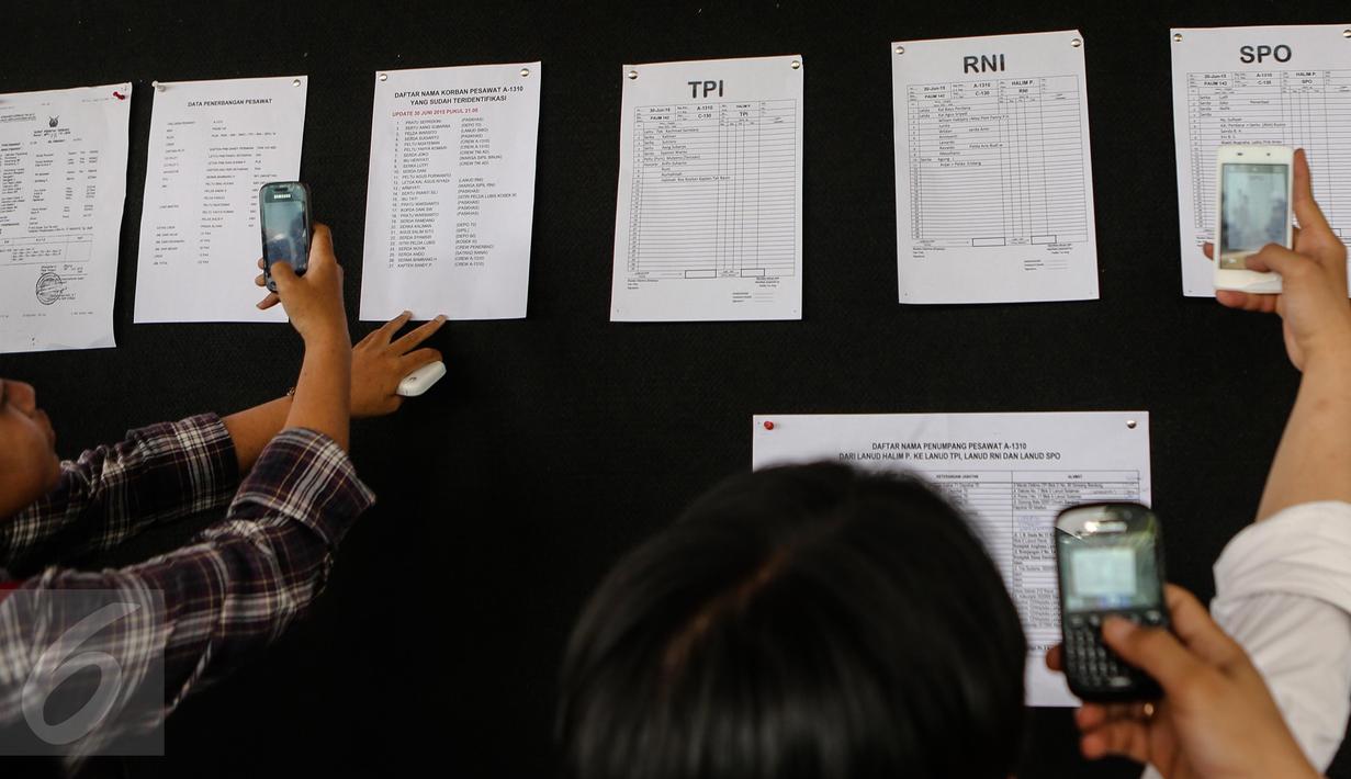 Awak media mengambil gambar daftar nama korban yang sudah berhasil diidentifkasi akibat jatuhnya pesawat Hercules C-130 milik TNI AU di Medan pada 30 Juni 2015, di Pangkalan Udara Halim Perdanakusuma, Jakarta, Rabu (1/7/2015). (Liputan6.com/Faizal Fanani)