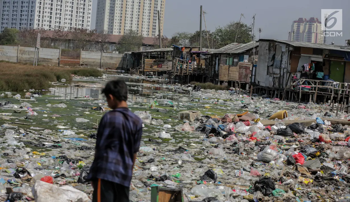 Seorang anak terlihat di dekat permukiman kumuh yang berdiri di atas tumpukan sampah di Kampung Bengek, Jakarta Utara, Selasa (3/9/2019). Permukiman kumuh ini berdiri di atas rawa yang membeku karena timbunan sampah plastik, kasur bekas hingga limbah rumah tangga. (Liputan6.com/Faizal Fanani)