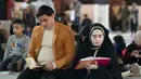 Memperbanyak bacaan Al Quran di akhir bulan merupakan bentuk konsistensi dalam beribadah juga sebagai bagian dari menghidupkan malam 10 malam terakhir Ramadan. Tampak dalam foto, seorang pria dan wanita Muslim Syiah membaca Al-Quran, membaca Al-Quran, saat melaksanakan Itikaf di Masjid Kufa, selatan Baghdad, Irak, pada 12 Maret 2026. (Qassem al-KAABI/AFP)