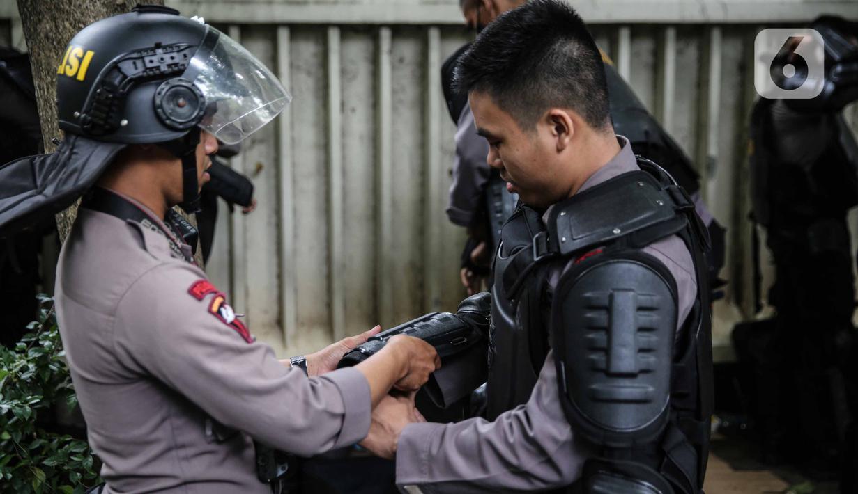 Personel Brimob bersiap mengenakan perlengkapan pelindung diri di Kawasan Bundaran HI, Jakarta, Selasa (13/10/2020). Sebanyak kurang lebih 12 ribu personel gabungan TNI, Polri dan Pemprov DKI Jakarta diterjunkan mengawal aksi tolak Undang-Undang Cipta Kerja Omnibus Law. (Liputan6.com/Faizal Fanani)
