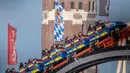 Pengunjung menaiki roller coaster di dekat Katedral Bunda Maria selama festival bir Oktoberfest di Munich, 24 September 2018. Oktoberfest adalah rangkaian festival terbesar di dunia yang diadakan setiap tahun di Jerman. (AFP/dpa/Peter Kneffel/Germany OUT)