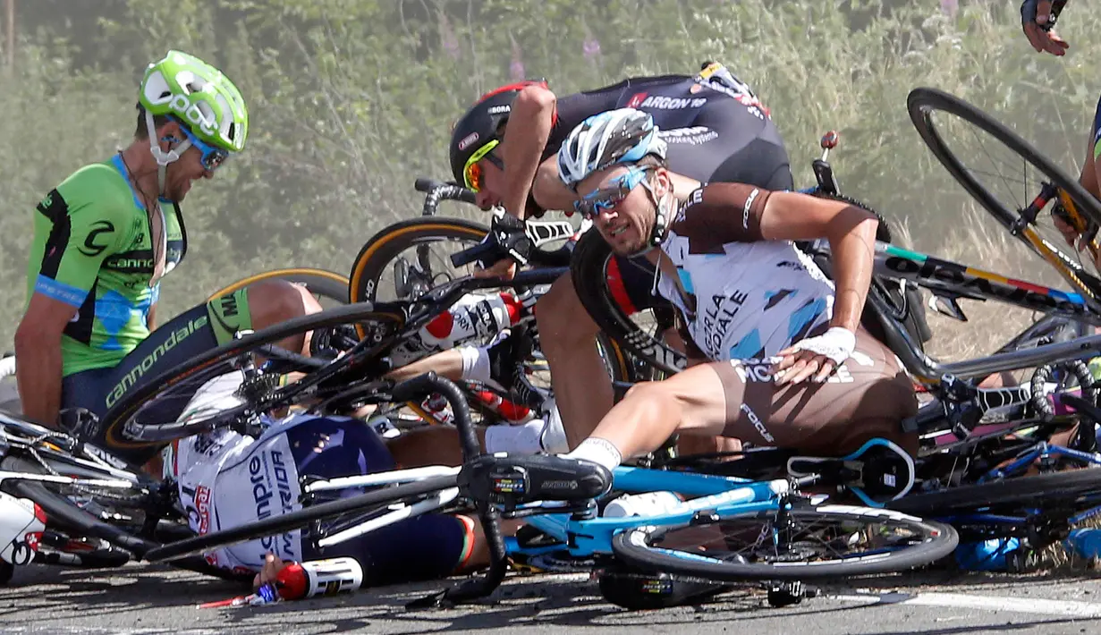 Seorang pebalap tampak tertindih sepedanya usai insiden kecelakaan yang melibatkan puluhan pebalap sepeda saat babak ketiga Tour de France dari Anvers ke Huy di Belgia, Senin (6/7/2015). (REUTERS/Eric Gaillard)