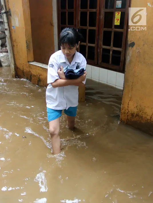 Seorang siswi melintasi banjir yang melanda Kampung Melayu, Jakarta Timur, Senin (25/6). (Liputan6.com/Arya Manggala)