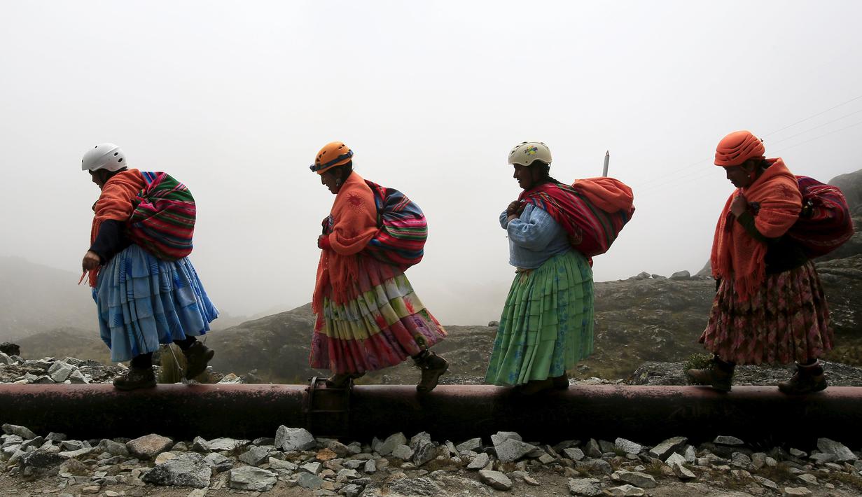 Perempuan suku Aymara saat mendaki Gunung Huayna Potosi, Bolivia (6/4). Perempuan suku Aymara yang berprofesi sebagai tukang masak dan angkut barang atau porter ini selalu mengenakan pakaian tradisional. (REUTERS/David Mercado)