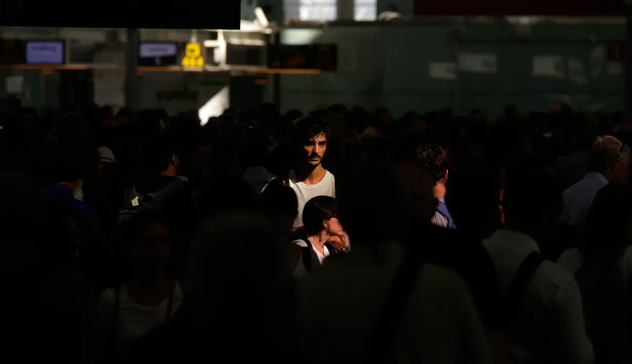Ekspresi penumpang saat menunggu di pintu area kontrol bandara Terminal 1 Barcelona-El Prat di Barcelona, Spanyol (4/8). Kejadian ini mengakibatkan penumpukan penumpang di pintu masuk dan keluar Bandara Barcelona-El Prat. (AP Photo/Manu Fernandez)
