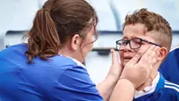 Suporter cilik Leicester City menangis setelah menyaksikan laga melawan West Ham United pada laga Liga Inggris di Stadion King Power, Minggu (28/5/2023). The Foxes resmi degradasi setelah mengakhiri musim di urutan 18 klasemen akhir dengan 34 poin. (AFP/Darren Staples)
