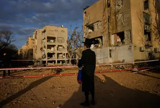 Serangan ini menandai eskalasi terbaru dalam konflik terbuka antara Israel dan Iran. Tampak dalam foto, warga melihat bangunan tempat tinggal yang rusak parah akibat serangan rudal Iran di Arad, Israel Selatan, Minggu, 22 Maret 2026. (AP Photo/Ohad Zwigenberg)