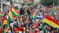 Orang-orang mengibarkan bendera Bolivia merayakan pengunduran diri Presiden Evo Morales di La Paz, Minggu (10/11/2019). Morales memutuskan mengundurkan diri buntut aksi protes yang dilatarbelakangi dugaan dirinya melakukan kecurangan dalam pemilu dalam beberapa pekan terakhir. (JORGE BERNAL/AFP)