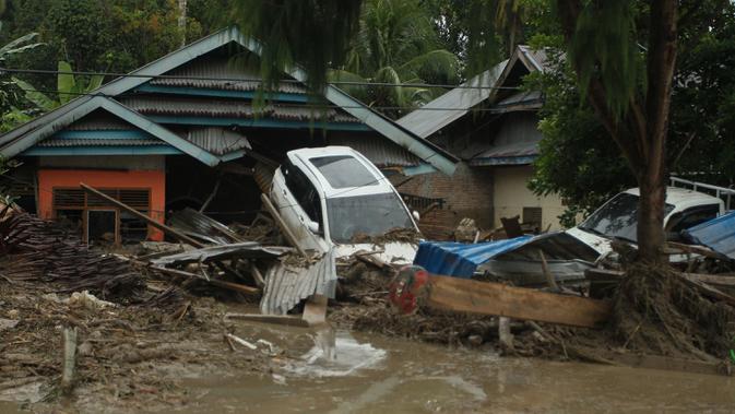 Kendaraan hanyut oleh banjir bandang di sebelah rumah-rumah di desa Radda di Kabupaten Luwu Utara, Sulawesi Selatan (14/7/2020). Hujan lebat yang mengakibatkan tiga sungai meluap telah menyapu rumah-rumah, kendaraan dan berbagai fasilitas umum di enam kecamatan di Kabupaten Luwu Utara. (AFP/Aryanto)