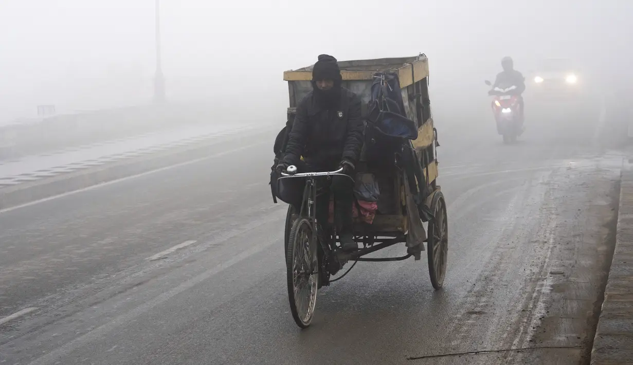 Seorang tunawisma mengendarai sepedanya di bawah kabut tebal pada pagi yang dingin di Srinagar, Kashmir yang dikuasai India, Jumat, 29 Desember 2023. (AP Photo/Dar Yasin)