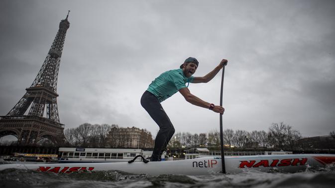 Peserta Nautic Paddle Race atau lomba dayung sambil berdiri melintas dekat Menara Eiffel di Sungai Seine, Paris, Minggu (8/12/2019). Sekitar 1000 pesaing ikut serta dalam lomba sejauh 11 kilometer menyeberangi sungai Seine dengan pemandangan kota Paris. (Photo by Olivier MORIN / AFP)