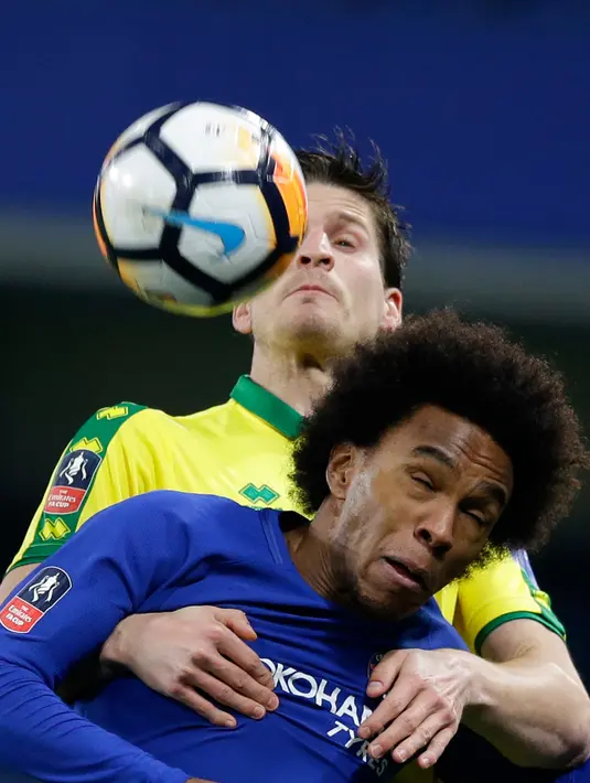 Pemain Chelsea Willian melompat untuk merebut bola dari pemain Norwich City Timm Klose pada laga ulangan babak ketiga Piala FA di Stadion Stamford Bridge, Rabu (17/1). Chelsea melaju ke babak keempat Piala FA lewat kemenangan dramatis. (AP/Alastair Grant)