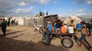 Warga dan anak-anak Palestina mengangkut jeriken berisi air bersih dari tangki air bergerak dengan gerobak keledai di kamp pengungsi Bureij di Jalur Gaza tengah pada 6 Oktober 2025. (Eyad BABA/AFP)