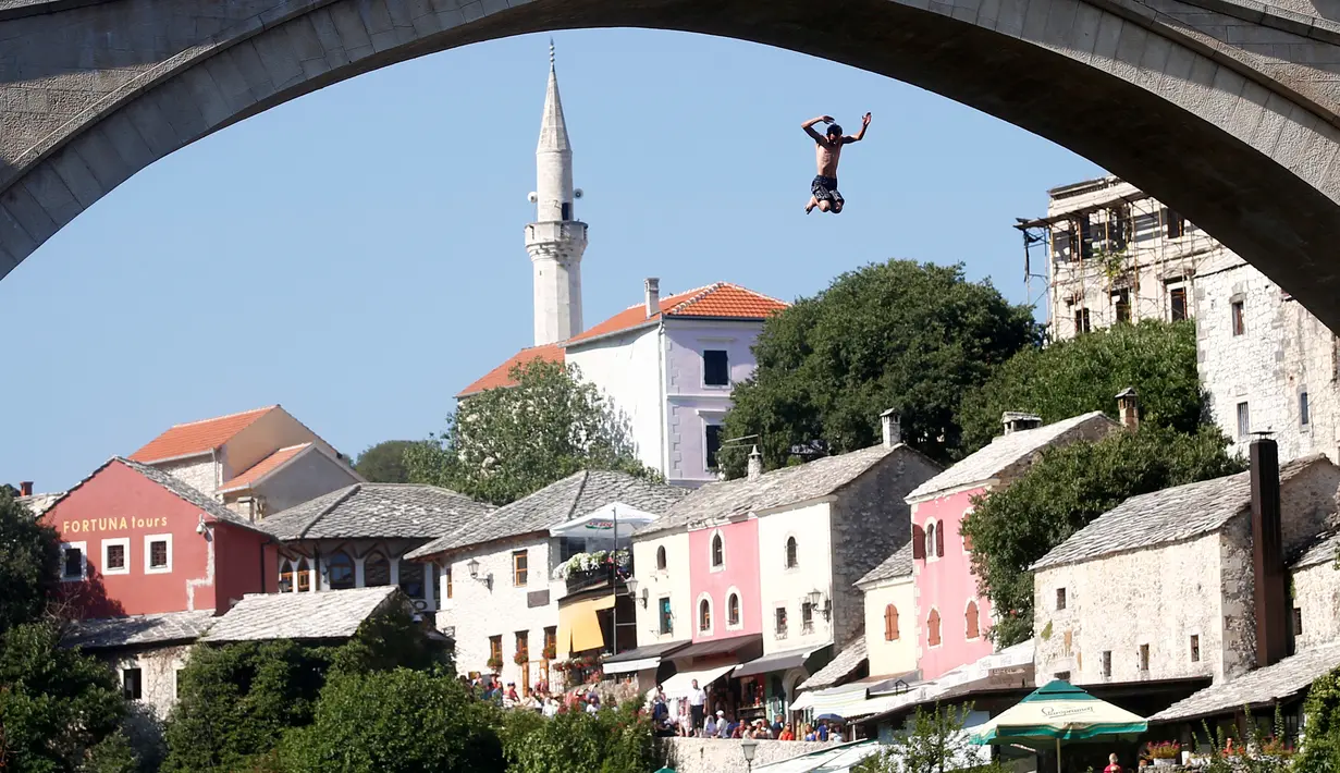 Aksi seorang peserta pria melompat dari jembatan saat mengkuti acara kompetisi menyelam tradisional 450 di Mostar, Bosnia dan Herzegovina, (31/7). (REUTERS/Dado Ruvic)