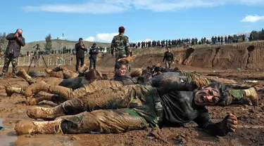 Pasukan perempuan Peshmerga menggulingkan badannya di tanah saat berlatihan dalam upacara kelulusan di Kota Soran, Irak, Rabu (12/2/2020). Latihan militer pasukan bersenjata Kurdi tersebut dilakukan sekitar 100 kilometer timur laut ibu kota otonomi wilayah Kurdi di Irak, Arbil. (SAFIN HAMED/AFP)