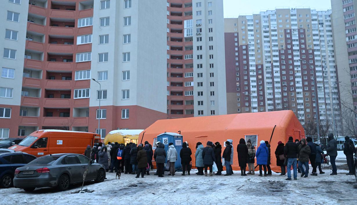 Antrean panjang ini dipicu oleh krisis energi dan suhu udara yang merosot hingga di bawah nol derajat Celsius (minus). Tampak dalam foto, warga setempat mengantre untuk menerima makanan hangat yang dibagikan oleh sukarelawan dari badan amal makanan yang berbasis di Amerika Serikat (AS), World Central Kitchen, membagikan makanan hangat kepada warga setempat di sebuah kawasan perumahan di Kyiv yang mengalami pemadaman listrik dan air akibat serangan Rusia yang menghantam sektor energi, Kamis 22 Januari 2026. (Sergei GAPON/AFP)