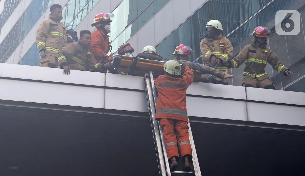 Petugas pemadam kebakaran mengevakuasi korban kebakaran di Gedung Cyber 1, Jakarta, Kamis (2/12/2021). Kebakaran Gedung Cyber 1 mengakibatkan satu orang meninggal dunia. (Liputan6.com/Herman Zakharia)