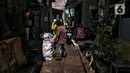 Warga membersihkan sampah sisa banjir di Kebalen, Jakarta, Minggu (21/2/2021). Banjir yang terjadi kemarin karena curah hujan yang tinggi meninggalkan sampah di rumah warga. (Liputan6.com/Johan Tallo)