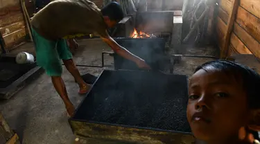 Seorang pria mengolah biji kopi robusta menggunakan alat tradisional di salah satu industri rumah tangga di Ulee Kareng, Aceh, Rabu (20/11/2019). Kopi yang diolah secara tradisional itu dijual dengan kisaran harga beragam tergantung kualitas. (CHAIDEER MAHYUDDIN/AFP)