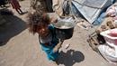 Seorang anak membawa panci saat berada dekat tenda tempat tinggalnya di kamp pengungsian di Sanaa, Yaman, (15/4). Mereka mengungsi akibat konflik di negaranya yang belum terseleasikan (AFP Photo / Mohammed Huwais)