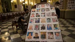 Pekerja memegang panel kayu setelah menempelinya dengan potret korban meninggal akibat virus corona di dalam Katedral, di Lima, Peru pada 13 Juni 2020. Misa Minggu di Katedral Lima dihadiri lebih dari 4.000 potret mereka yang telah meninggal dalam pandemi Covid-19 yang menyebar di Peru. (AP Photo/Ro