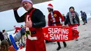 Sejumlah pengunjung berkostum Sinterklas bersiap untuk berselancar dalam acara Surfing Santa yang berlangsung di Pantai Cocoa, Florida, Amerika Serikat, Selasa (24/12/2024) waktu setempat. (AFP/Giorgio Viera)