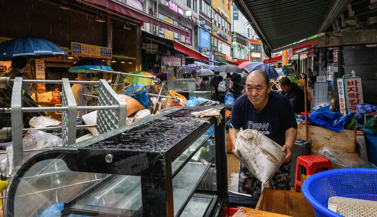 <p>Seorang pria membersihkan puing-puing dan barang-barang rusak di luar tokonya di Pasar Namseong yang bersejarah di distrik Gangnam Seoul (9/8/2022). Dilansir Yonhap, Selasa (9/8/2022), hujan yang terjadi di Korea Selatan adalah yang terparah dalam 80 tahun terakhir. (AFP/Anthony Wallace)</p>