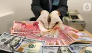Karyawan menunjukkan uang rupiah dan dolar AS di Jakarta, Rabu (30/12/2020). Nilai tukar rupiah di pasar spot ditutup menguat 80 poin atau 0,57 persen ke level Rp 14.050 per dolar AS. (Liputan6.com/Johan Tallo)
