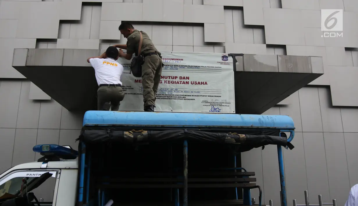 Petugas Satpol PP menyegel Diskotek Exotic dengan memasang banner penutup di Mangga Besar, Jakarta, Kamis (19/4). Pemprov DKI menutup Diskotek Exotic setelah ditemukan pengunjung yang meninggal diduga akibat overdosis narkoba. (Liputan6.com/Arya Manggala)