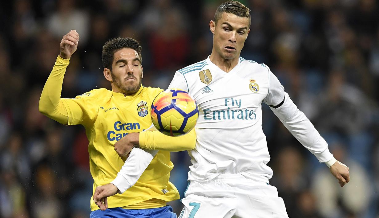 Cristiano Ronaldo (kanan) berebut bola dengan pemain Las Palmas, Pedro Bigas Rigo pada laga La Liga Santander di Santiago Bernabeu stadium, Madrid, (5/11/2017). Real Madrid menang 3-0. (AFP/Gabriel Bouys)