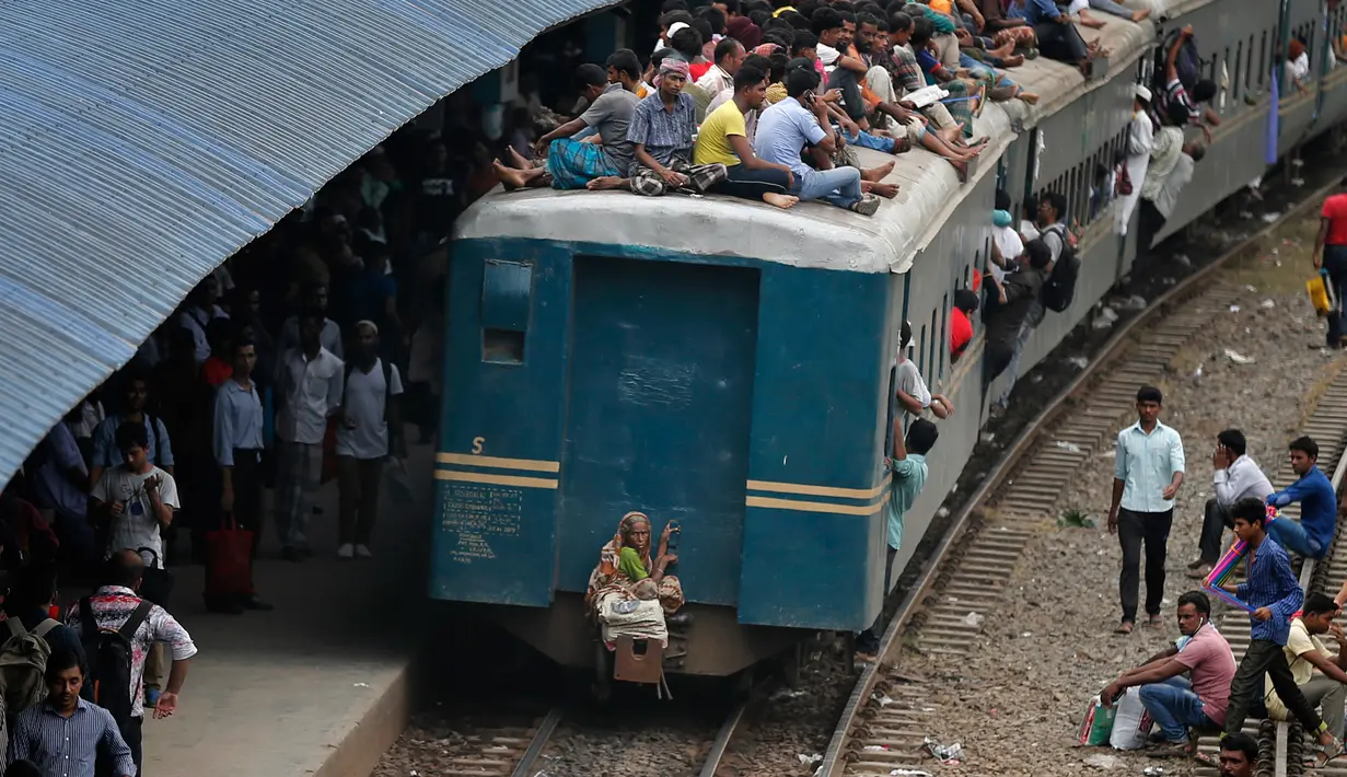 Penumpang berada di atap kereta api saat akan pulang kampung di stasiun kereta api di Dhaka, Bangladesh, (22/6). Ribuan yang bekerja di Dhaka pulang ke kampung halamannya untuk merayakan lebaran bersama keluarganya. (AP Photo/A.M.Ahad)