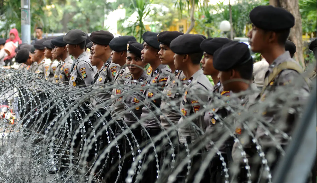 Petugas polisi berjajar menutup Jalan Medan Merdeka Barat, Senin (1/5). Aksi perayaan Hari Buruh Internasional oleh ribuan buruh tertahan di depan Kementerian Pariwisata akibat penutupan Jalan medan Merdeka Barat. (Liputan6.com/Helmi Fithriansyah)