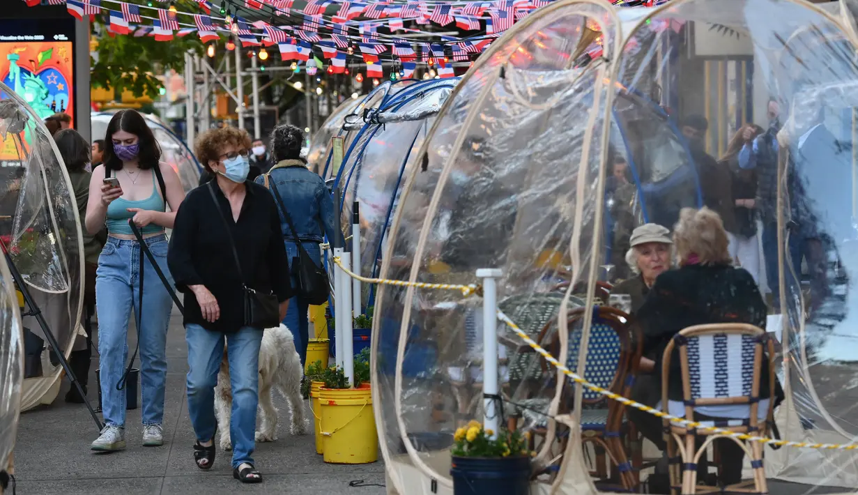 Orang-orang menikmati makanan di dalam tenda plastik untuk menjaga jarak di sebuah restoran di Manhattan, New York City, Kamis (15/10/2020). Konsep gelembung luar angkasa ini menawarkan sensasi tersendiri sekaligus berjaga-jaga dari resiko penularan COVID-19 bagi para pelanggan. (Angela Weiss/AFP)
