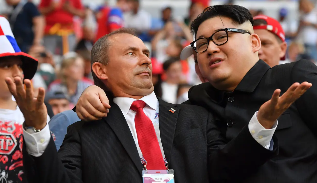 Peniru Presiden Rusia, Vladimir Putin dan pemimpin Korea Utara, Kim Jong-un berpose selama menyaksikan laga penyisihan Grup A Piala Dunia 2018 antara Uruguay vs Rusia di Samara Arena, Senin (25/6). Uruguay berhasil melumat Rusia 3-0. (AFP/EMMANUEL DUNAND)