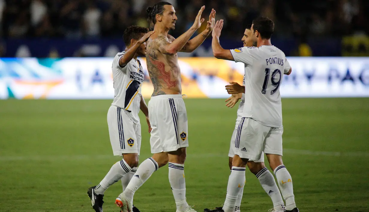 Penyerang LA Galaxy, Zlatan Ibrahimovic berselebrasi bersama rekannya setelah mencetak gol pada pertandingan MLS di StubHub Center di Carson, California (29/7). Ibrahimovic mencetak hattrick pertamanya bersama LA Galaxy. (AFP Photo/Katharine Lotze)