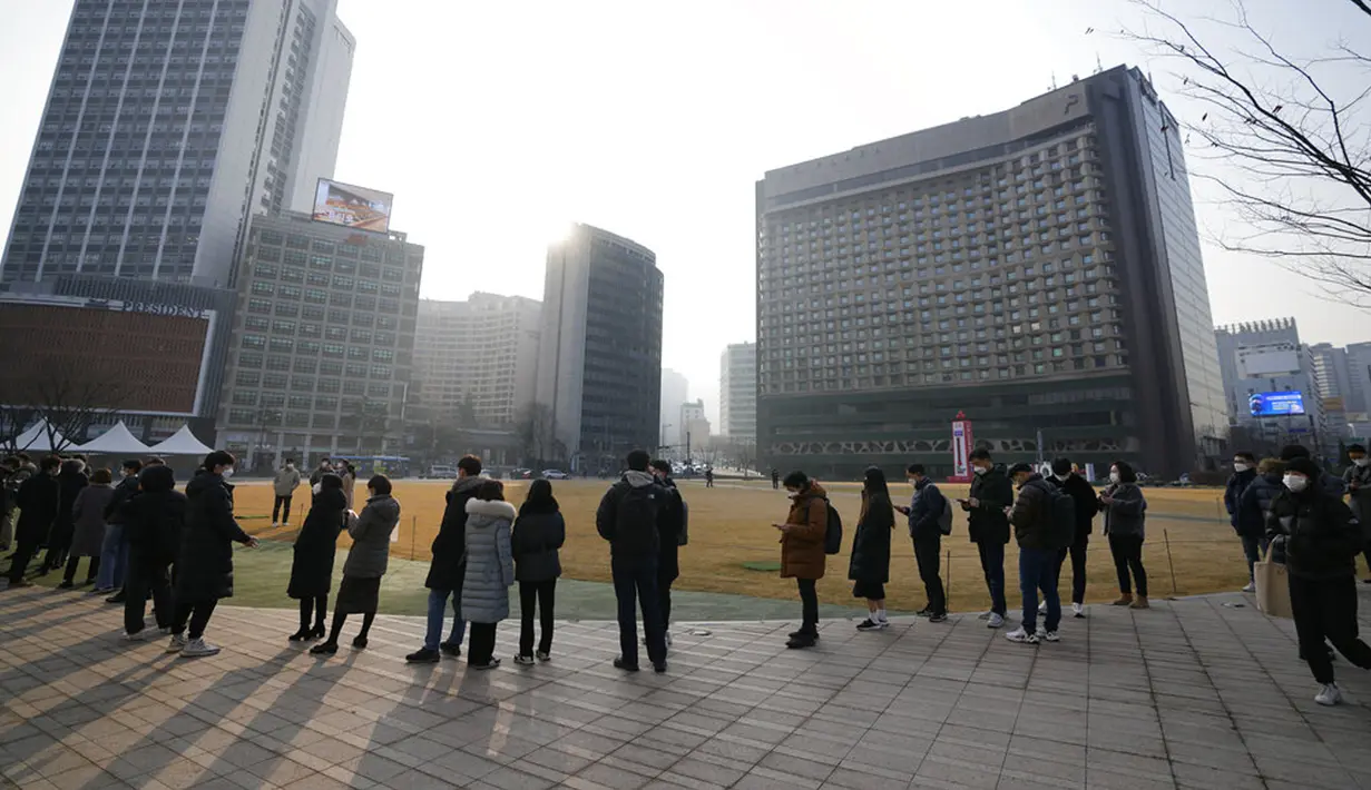 Orang-orang mengantre untuk tes virus corona COVID-19 sambil menjaga jarak sosial di klinik skrining sementara untuk virus corona dekat Balai Kota Seoul, Seoul, Korea Selatan, Rabu (26/1/2022). (AP Photo/Lee Jin-man)