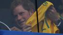 Dari balik kaca pelindung, sambil terus memegangi kaos Timnas Brasil, Pangeran Harry melihat langsung aksi Neymar dkk berlaga melawan Kamerun di Stadion Nasional Brasil, (24/6/2014). (REUTERS/Ueslei Marcelino)  