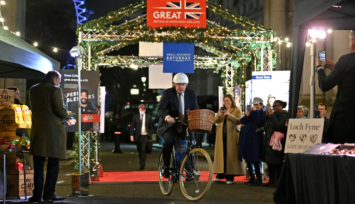 Perdana Menteri Inggris Boris Johnson mengendarai sepeda saat kunjungannya ke pasar Makanan dan Minuman Inggris yang didirikan di Downing Street, London, 30 November 2021. Sebanyak 12 bisnis dari seluruh Inggris memiliki kios untuk memamerkan produk mereka. (JUSTIN TALLIS/AFP/POOL)