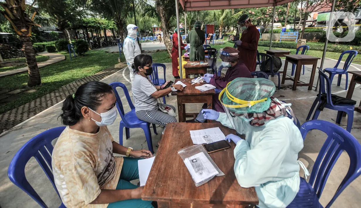Petugas memeriksa warga saat tes usap PCR di Taman Pintar, Kayu Putih, Pulogadung, Jakarta Timur, Selasa (8/6/2021). Saat ini, RW 09 dan 10 Kelurahan Kayu Putih dalam status zona merah atau karantina wilayah sejak 4 Juni setelah 22 orang terkonfirmasi positif COVID-19. (merdeka.com/Iqbal S. Nugroho)
