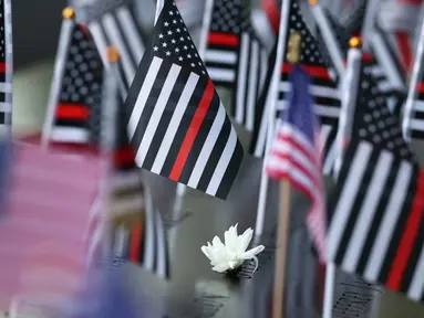 Bunga dan bendera Amerika Serikat terlihat di atas nama-nama korban serangan teroris 9/11 di kolam refleksi Menara Selatan selama Upacara Peringatan Tahunan 9/11 di Museum dan Monumen Nasional 9/11 di Kota New York pada 11 September 2025. (Michael M. Santiago/Getty Images North America/Getty Images via AFP)