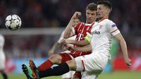 Pemain Bayern, Thomas Mueller (kiri) berebut bola dengan pemain Sevilla, Clement Lenglet pada leg kedua perempat final Liga Champions di Allianz Arena stadium, Munich, (11/4/2018). Bayern lolos ke semifinal dengan agregat 2-1. (AP/Matthias Schrader)